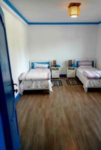 a room with three beds and a wooden floor at Casa cu Flori in Mila Douăzeci şi Trei
