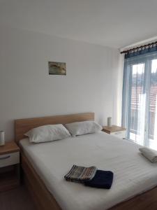 a bedroom with a large white bed with a window at Ivana apartman 2 in Lovište