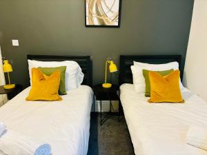 two beds with yellow pillows sitting next to each other at Boutique Docks Apartment - Parking in Gloucestershire