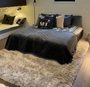 a bed with a black comforter and pillows on a rug at Timmerstugan Dalarna - nära Mora och Orsa Grönklitt in Orsa
