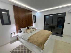 a bedroom with a large bed with a wooden headboard at Villa Benbienn piscine iptv Billard américain wifi illimité très bon emplacement in Taguermess +45 photos