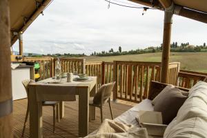 a patio with a couch and a table on a deck at Glamping Tenuta Radici in Castelnuovo della Misericordia