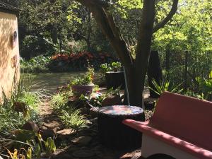 a bench sitting next to a tree in a garden at ilyn pottery cottage in Pretoria