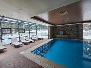 a swimming pool in a building with chairs around it at Forest Chamkoria Apartment in Borovets