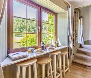 a kitchen with a breakfast bar with stools and a window at Rosemount Bothy - Highland Cottage in Garve