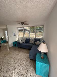 a living room with a blue couch and a ceiling fan at Cozy house with sea view! in Luquillo