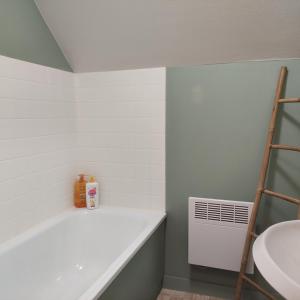 a bathroom with a white bath tub next to a sink at maison proche plage du pouliguen baie de la baule in Le Pouliguen