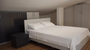 a bedroom with a white bed and a black cabinet at City Gallery by Sienna in Skopje +3 photos