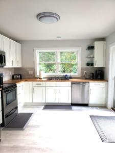 Una cocina con gabinetes blancos y un fregadero y una ventana. en 18-Acre Waterfront Sanctuary Peace and Privacy, en Ridge