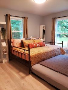 Un dormitorio con una cama y dos ventanas. en 18-Acre Waterfront Sanctuary Peace and Privacy, en Ridge