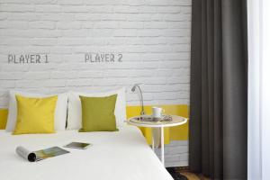 Una cama con almohadas amarillas y blancas y una mesa. en Ibis Styles Budapest Center en Budapest