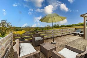 a patio with chairs and an umbrella on a deck at Gîte Bellevue - cosy huisje op vakantiepark in Jayac