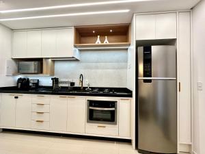 a kitchen with white cabinets and a stainless steel refrigerator at Apto Itapema NOVO 2 quartos e 2bwc -2 garagens - Prédio com Piscina in Itapema