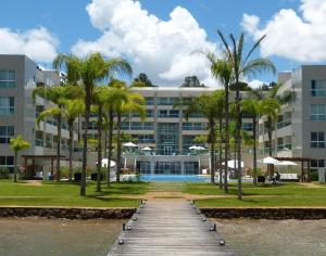 a boardwalk leading to a large building with palm trees at Fabuloso - Brisas do Lago in Brasília