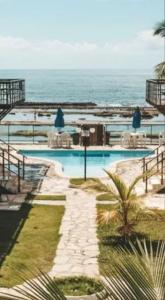 a swimming pool with the ocean in the background at Apartamento pé na areia na praia de enseadas dos corais-Gaibu, em frente as piscinas naturais in Cabo de Santo Agostinho