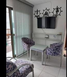 a living room with a table and chairs and a tv at Apartamento pé na areia na praia de enseadas dos corais-Gaibu, em frente as piscinas naturais in Cabo de Santo Agostinho