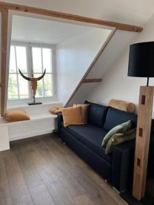 a living room with a blue couch and a window at De Gouwe Leeuw in Woerdense Verlaat