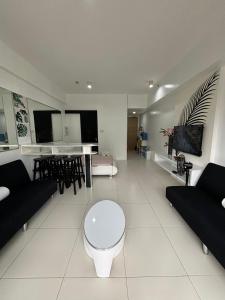 纳苏格布Beach condos at Pico de Loro Cove - Wi-Fi & Netflix, 42-50''TVs with Cignal cable, Uratex beds & pillows, equipped kitchen, balcony, parking - guest registration fee is not included的客厅配有黑色家具,铺有白色地板。