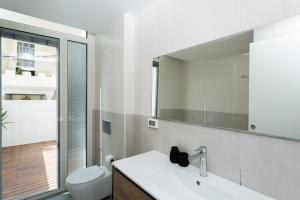 a bathroom with a sink and a toilet and a mirror at Mate Kalischer - By HOMY in Tel Aviv +73 photos