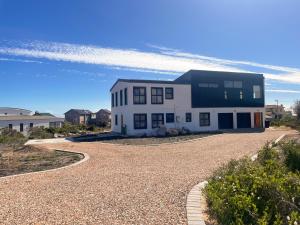 a large white house on a gravel road at 155 Hangklip self catering in Pringle Bay