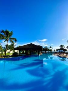 a large swimming pool with a building and palm trees at Fleixeiras Eco Residence in Trairi