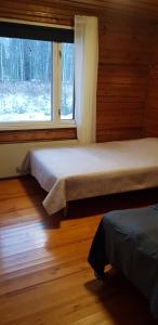 two beds in a room with a window at Cozy cottage on lake in Iokela