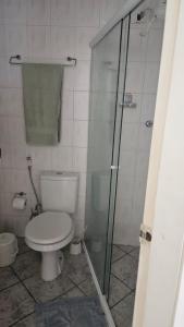 a bathroom with a toilet and a glass shower at Apartamento aconchegante a 100m da praia in Praia Grande