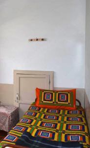 a bed with a colorful blanket and two pillows at City Guest House in Bhuj