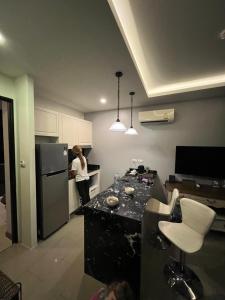 a woman standing in a kitchen next to a refrigerator at Palmyrah Surin Beach Residence in Ban Lum Fuang