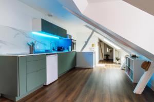 a large kitchen with blue cabinets in a attic at La Mansarde Cauchoise - Centre ville - Au calme in Rouen +13 photos