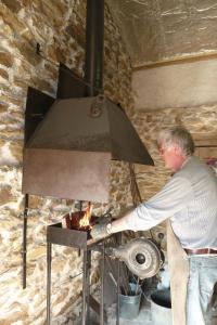 un uomo sta cucinando sul fuoco in un forno di B&B L'Atelier du Presbytère a Saint-Maugan