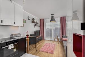 a kitchen with white cabinets and a pink rug at Soft Loft Legnicka in Wrocław