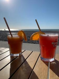 two drinks sitting on a wooden table near the ocean at Spacieuse Maison Bleue, au centre des Cordiers in Le Tréport +24 photos
