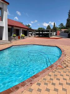 a swimming pool with blue water in a yard at On Hill Lodge in Bloemfontein