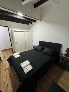 a bedroom with a black bed with two towels on it at Complejo PARAÍSO CHAPADMALAL in Chapadmalal
