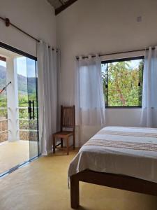 ein Schlafzimmer mit einem Bett und einem großen Fenster in der Unterkunft Casa Mirante da Serra in Cavalcante