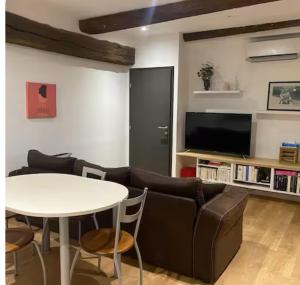 un soggiorno con un divano, un tavolo e una TV di Appartements du val a Vitré