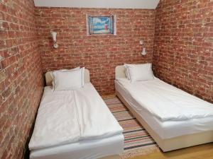 two beds in a room with a brick wall at Tabán Apartman in Dunakeszi