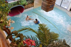 two people in a swimming pool at a resort at Vakantiewoning met serre en airconditioning in Tzummarum