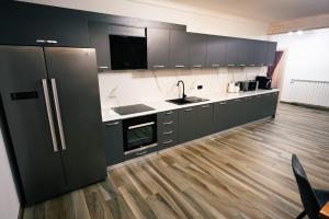 a kitchen with black cabinets and a wooden floor at Vila Tudor in Borşa