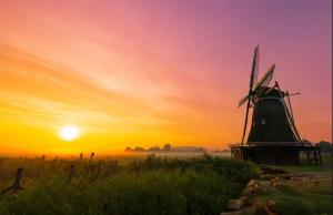 a sunset with a windmill in a field at Huisje over de IJssel in Zwolle