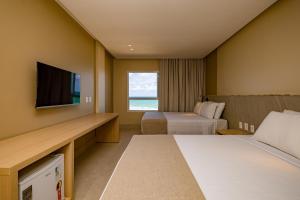 a hotel room with two beds and a flat screen tv at Costeira Palace Beach Resort All Inclusive in Natal