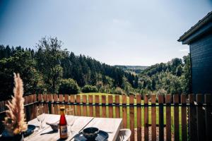 a wooden fence with a table and a bottle of wine at # A Mont Nos'Hôtes in Malmedy
