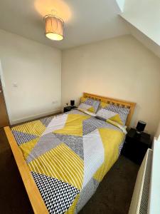 a bedroom with a bed with a yellow and black quilt at Stunning Modern 2 Bedroom Apartment - Perfect Getaway in Manchester