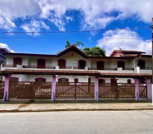 a white house with a wooden fence in front of it at Pousada Stilo Ponta Negra in Ubatuba