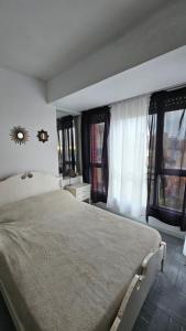 a bedroom with a large bed and windows at Departamento Miramar frente al Mar - Edificio Stella Maris in Miramar