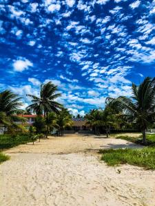 einen Strand mit Palmen und einem wolkigen Himmel in der Unterkunft Casa Itamaracá in Itamaracá