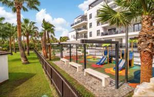 a playground in front of a building with palm trees at Nasila Golf&Beach in Motril