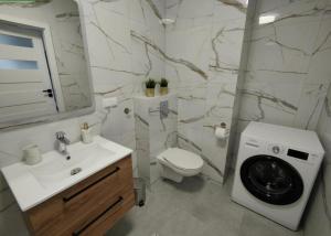 a bathroom with a sink and a washing machine at Apartament Jan in Szczytno