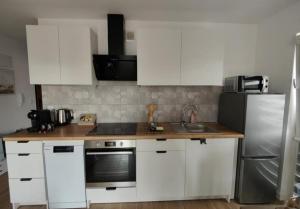 a kitchen with white cabinets and a stainless steel refrigerator at Apartament Jan in Szczytno